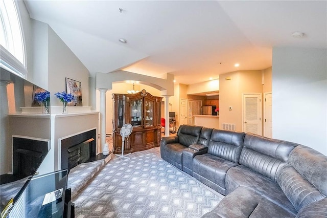 living area featuring visible vents, a fireplace with raised hearth, arched walkways, lofted ceiling, and ornate columns