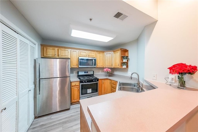 kitchen featuring visible vents, appliances with stainless steel finishes, a peninsula, open shelves, and a sink