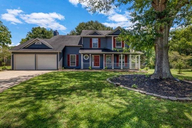 2505 Tiffany Ct SE, Conyers, GA 30013 - view of front of house featuring an attached garage, a front yard, driveway, and covered porch