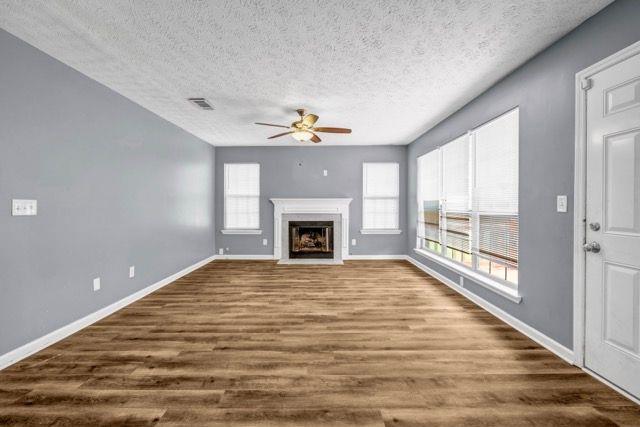 2505 Tiffany Ct SE, Conyers, GA 30013 - unfurnished living room featuring a ceiling fan, dark wood-style floors, baseboards, a textured ceiling, and a fireplace with flush hearth