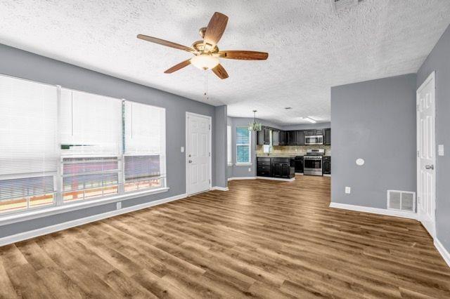 2505 Tiffany Ct SE, Conyers, GA 30013 - unfurnished living room with a textured ceiling, dark wood-style floors, baseboards, and a ceiling fan
