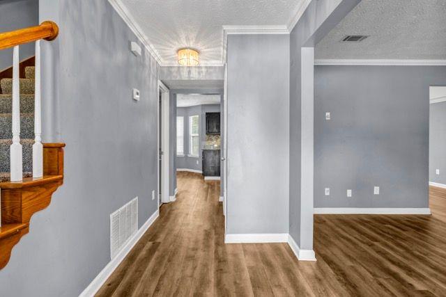 2505 Tiffany Ct SE, Conyers, GA 30013 - corridor with stairway, baseboards, wood finished floors, crown molding, and a textured ceiling