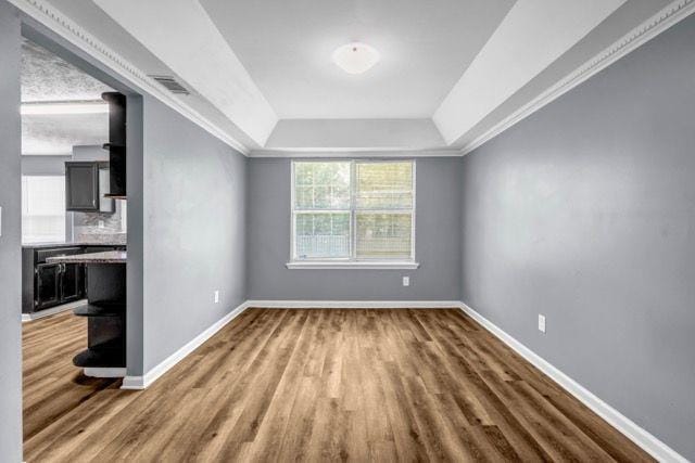 2505 Tiffany Ct SE, Conyers, GA 30013 - empty room with a tray ceiling, wood finished floors, baseboards, and ornamental molding