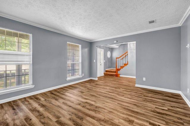 2505 Tiffany Ct SE, Conyers, GA 30013 - empty room with a textured ceiling, ornamental molding, wood finished floors, baseboards, and stairway