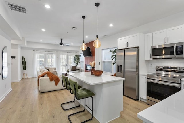 kitchen featuring visible vents, white cabinetry, open floor plan, light countertops, and appliances with stainless steel finishes