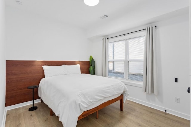 bedroom featuring visible vents, baseboards, and wood finished floors