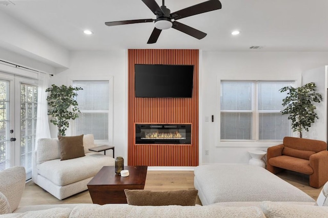 living room with visible vents, a glass covered fireplace, wood finished floors, french doors, and recessed lighting