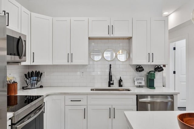 kitchen with decorative backsplash, stainless steel appliances, light countertops, white cabinetry, and a sink