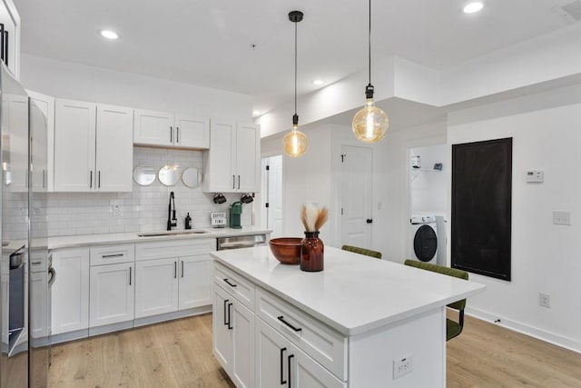 kitchen with pendant lighting, light countertops, a sink, and white cabinets