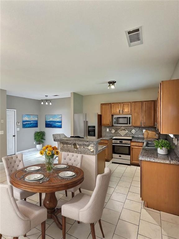 kitchen with light tile patterned flooring, stainless steel appliances, sink, and backsplash