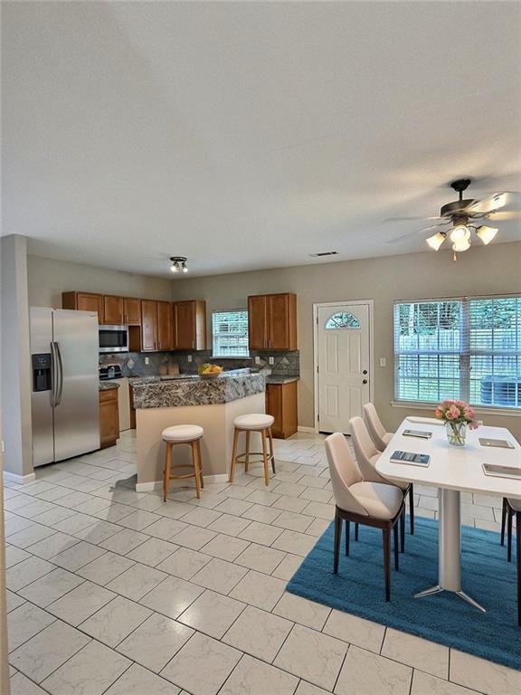 tiled dining space featuring plenty of natural light and ceiling fan