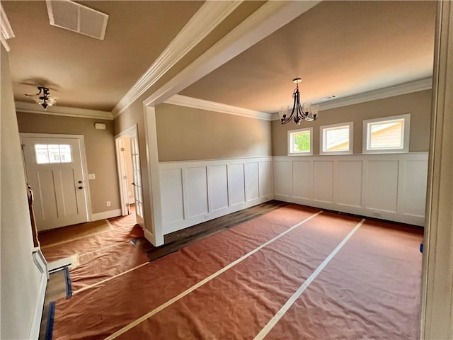 foyer entrance with crown molding and a chandelier