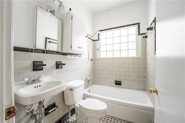 full bathroom with tile walls, tiled shower / bath combo, and toilet