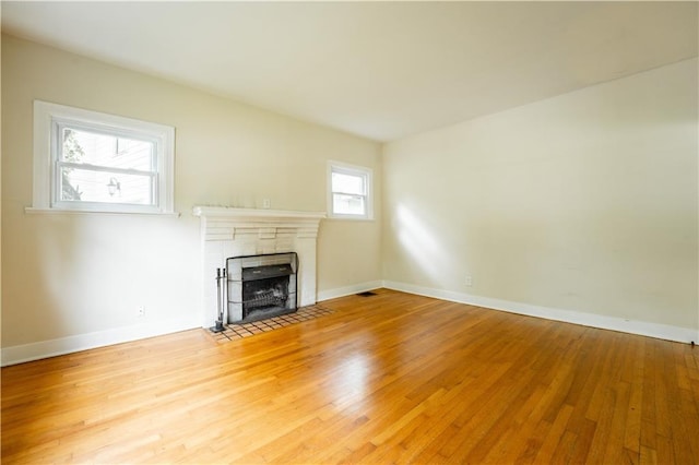 unfurnished living room with wood-type flooring and a tile fireplace