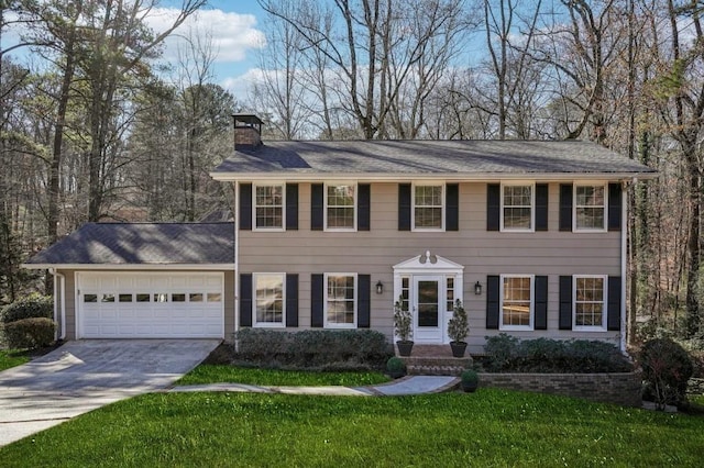 colonial home featuring a garage, a chimney, a front lawn, and concrete driveway