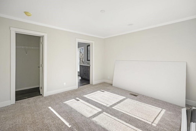 unfurnished bedroom featuring carpet floors, ensuite bathroom, a closet, and crown molding