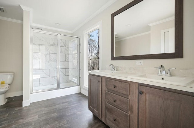 bathroom with toilet, ornamental molding, a shower with shower door, and hardwood / wood-style floors