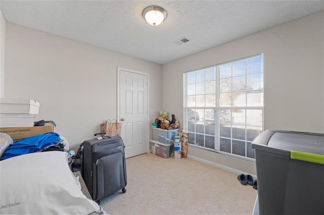 bedroom with light colored carpet and a textured ceiling