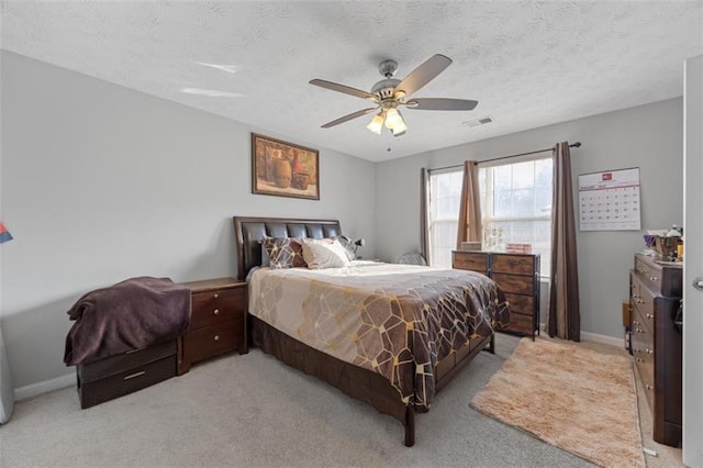 bedroom featuring ceiling fan, light carpet, and a textured ceiling