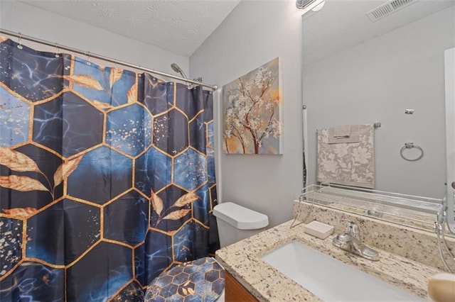 bathroom featuring walk in shower, vanity, toilet, and a textured ceiling