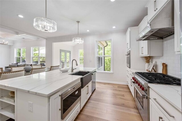 kitchen featuring a sink, white cabinets, under cabinet range hood, stainless steel appliances, and light wood-style flooring