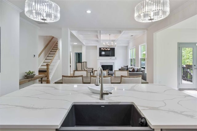 kitchen featuring an inviting chandelier, a sink, a fireplace, recessed lighting, and coffered ceiling