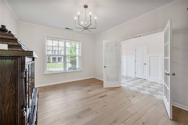 unfurnished dining area with visible vents, ornamental molding, a chandelier, french doors, and light wood-style flooring