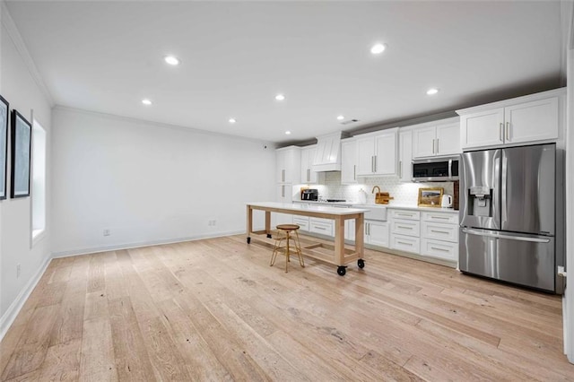 kitchen with decorative backsplash, premium range hood, ornamental molding, stainless steel appliances, and white cabinetry