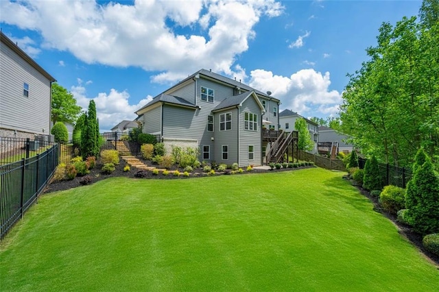 back of house with a lawn, a fenced backyard, and stairway