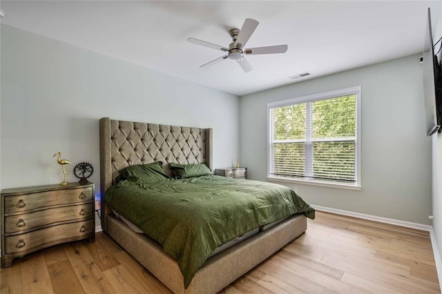 bedroom with baseboards, a ceiling fan, wood finished floors, and visible vents