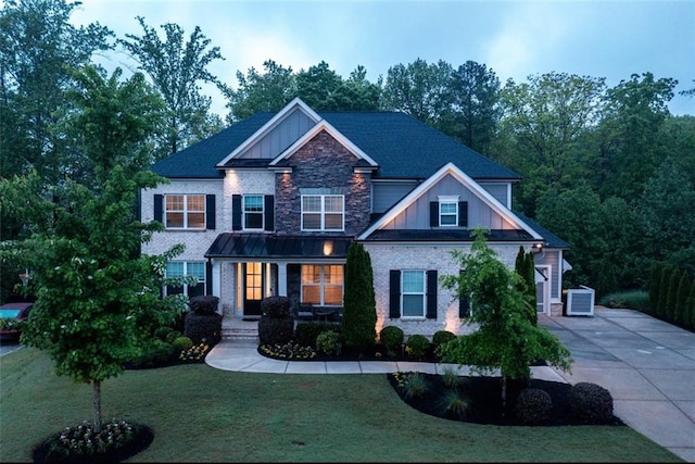 craftsman inspired home featuring board and batten siding, a porch, central AC unit, a front lawn, and concrete driveway