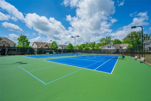 view of tennis court featuring community basketball court and fence