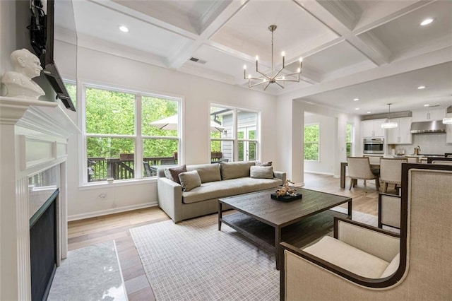 living area featuring light wood-style floors, a notable chandelier, plenty of natural light, and a high end fireplace