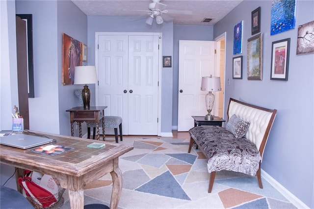 living area with ceiling fan and a textured ceiling