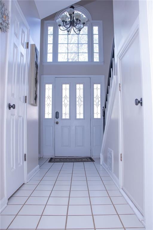 foyer featuring light tile patterned floors, an inviting chandelier, and a high ceiling