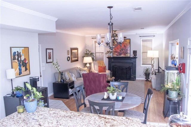 dining space featuring crown molding, light hardwood / wood-style floors, and a notable chandelier