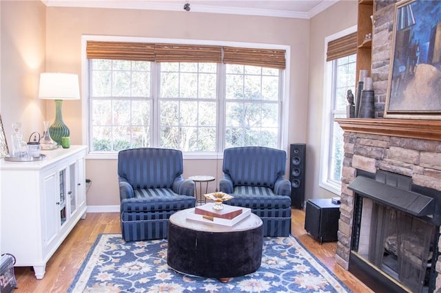 living area with a fireplace, light wood-type flooring, plenty of natural light, and crown molding