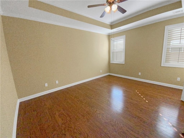 unfurnished room featuring baseboards, visible vents, ceiling fan, wood finished floors, and a tray ceiling