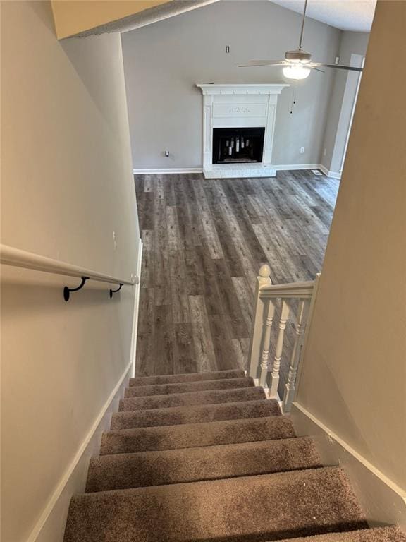 671 Peach Crossing Dr, Dallas, GA 30132 - staircase featuring ceiling fan, a glass covered fireplace, wood finished floors, and lofted ceiling
