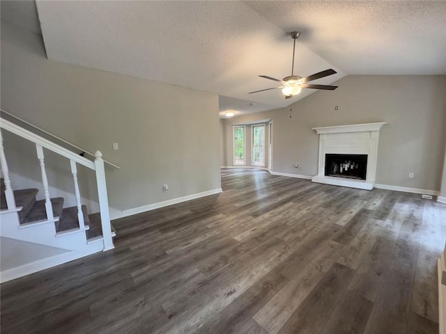 671 Peach Crossing Dr, Dallas, GA 30132 - unfurnished living room featuring a ceiling fan, dark wood-style floors, a textured ceiling, lofted ceiling, and a fireplace with raised hearth