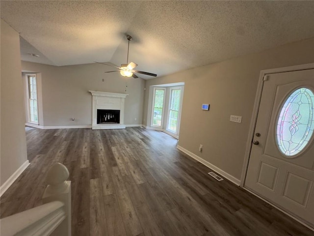 671 Peach Crossing Dr, Dallas, GA 30132 - unfurnished living room featuring ceiling fan, a textured ceiling, dark wood finished floors, a fireplace with raised hearth, and lofted ceiling