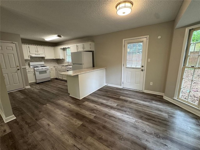 671 Peach Crossing Dr, Dallas, GA 30132 - kitchen with white appliances, a peninsula, a textured ceiling, dark wood-type flooring, and light countertops