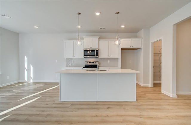 kitchen featuring pendant lighting, sink, white cabinetry, a kitchen island with sink, and stainless steel appliances