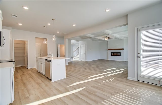 kitchen with beamed ceiling, a wealth of natural light, coffered ceiling, a kitchen island with sink, and pendant lighting