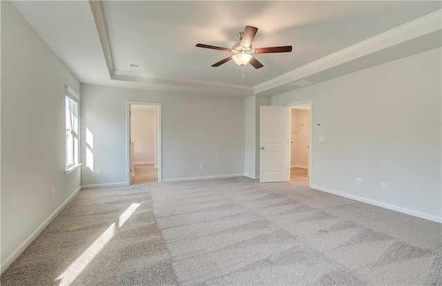 carpeted empty room with ornamental molding, ceiling fan, and a raised ceiling