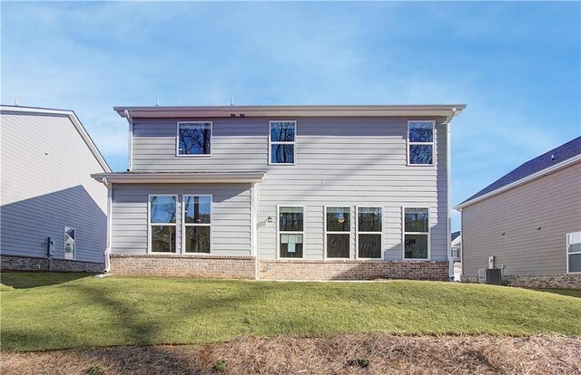 rear view of house with central AC unit and a lawn