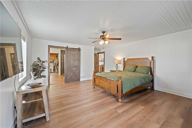 bedroom featuring ornamental molding, ceiling fan, a barn door, and light hardwood / wood-style flooring