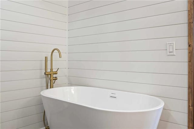 bathroom featuring a tub and wood walls