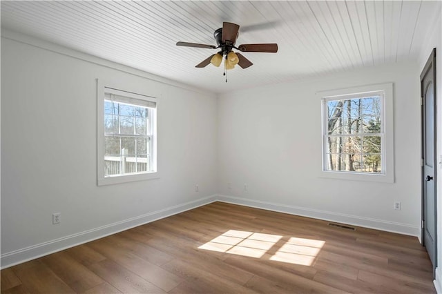 spare room featuring a healthy amount of sunlight, ceiling fan, and dark hardwood / wood-style flooring