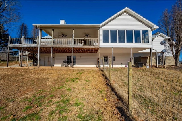 rear view of house featuring ceiling fan, a lawn, a deck, and a patio area